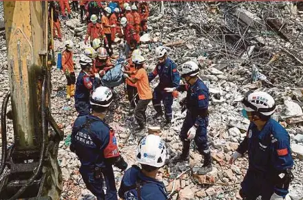 ?? AFP PIC ?? Rescuers carrying the body of a victim trapped under the rubble of a collapsed building in Mandalay, Myanmar, on Wednesday.