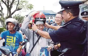  ??  ?? SHAFIE memakaikan topi keledar kepada penunggang motosikal sebagai gimik perasmian Majlis Pelancaran Op Selamat 13 di Plaza Merdeka, Kuching.