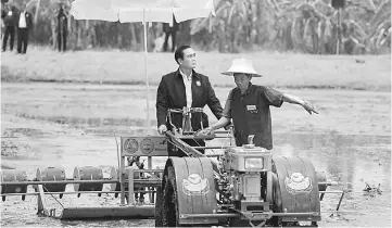  ??  ?? Prayuth rides on a tractor at a farmer school in Suphan Buri province. — Reuters photo