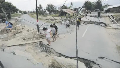  ?? Picture: EPA-EFE ?? STOP AND GO. Residents navigate the broken street of Petobo in Palu, central Sulawesi in Indonesia, yesterday. The village was totally destroyed by a landslide, triggered by strong earthquake­s.