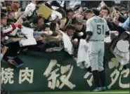  ?? EUGENE HOSHIKO — THE ASSOCIATED PRESS ?? Seattle’s Ichiro Suzuki gives his autograph to fans prior to an exhibition game between the Mariners and the Yomiuri Giants at Tokyo Dome in Tokyo March 17.