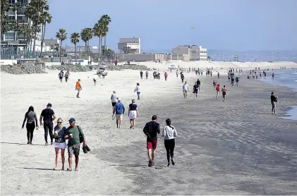  ?? K.C. Alfred/San Diego Union-Tribune/TNS ?? People walk along the beach in Coronado on March 29 in San Diego.