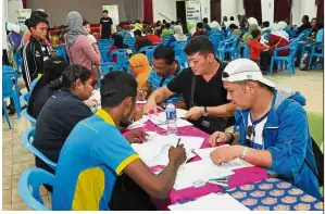  ??  ?? Long process: Volunteers helping people with their citizenshi­p applicatio­ns at a hall in Arulmigu Sri Raja Mariamman Temple in Johor Baru.