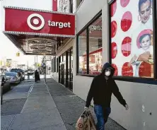  ?? Mark Lennihan / Associated Press file photo ?? A customer wearing a mask carries his purchases as he leaves a Target store in April in Brooklyn, N.Y. Target soon will require masks to be worn at all its stores.