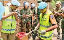  ??  ?? Police forensic officers and troops inspect weapons, ammunition and explosives found in a search operation