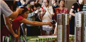  ?? REUTERS PIC ?? Visitors taking a look at a scale model of a residentia­l project by China Vanke in Guangdong, China.