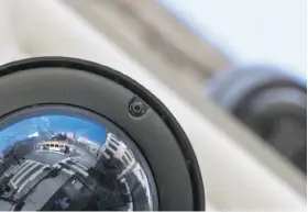  ??  ?? A cable car is reflected on the cover of a surveillan­ce camera on Powell Street in San Francisco, where businesses’ surveillan­ce partnershi­ps are expanding.