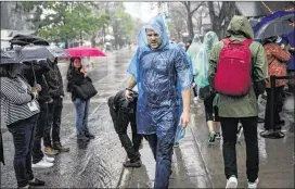  ?? TAMIR KALIFA / AMERICAN-STATESMAN ?? SXSW Interactiv­e attendees line up on Rainey Street for an event Saturday. The large crowds and rainy weather fueled strong demand for ride-hailing apps, and Fasten and RideAustin were down for several hours that evening.