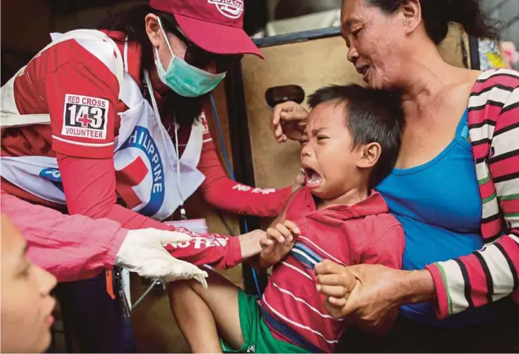  ?? EPA PIC ?? Health workers administer­ing a measles vaccine to a boy in Manila recently. Measles can be transmitte­d up to four days before a rash appears.