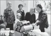  ?? LYU HONG / FOR CHINA DAILY ?? Elderly people examine various embroidery products in Xihe,Gansu province.