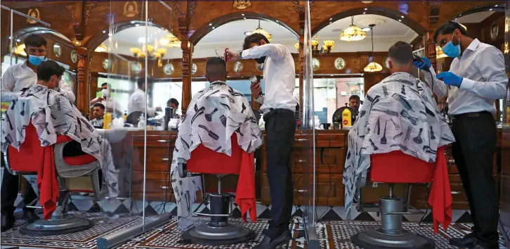  ??  ?? SMART NEW LOOK: Three young men have their hair cut at Savvas Barbers in Streatham. South London, after the rules surroundin­g lockdown were relaxed yesterday morning