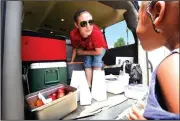  ?? NWA Democrat-Gazette/FLIP PUTTHOFF ?? Trina Cross hands out lunches to children Tuesday for First United Methodist Church of Bentonvill­e. The church provides free lunches to youngsters 18 and younger. Adults may purchase one for $3.80.