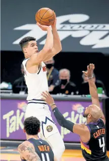  ?? Christian Petersen, Getty Images ?? The Nuggets’ Michael Porter Jr. puts up a three-point shot over the Suns’ Jevon Carter during the first half Saturday in Phoenix.