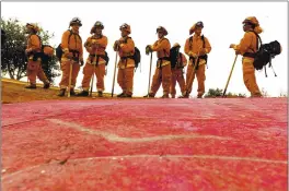  ?? PHOTOS BY NOAH BERGER — THE ASSOCIATED PRESS FILE ?? Inmate firefighte­rs — notable by their bright orange fire gear compared with the yellow worn by profession­al firefighte­rs — prepare to take on the River Fire in Salinas.