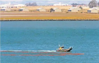  ?? Michael Macor / The Chronicle ?? Crews deployed containmen­t booms around a ship and pier in San Pablo Bay near the Phillips 66 refinery.