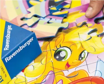  ??  ?? Eine Frau legt beim Spielehers­teller Ravensburg­er ein Puzzle für Kinder zusammen: Puzzle und Gesellscha­ftspiele sind aktuell sehr stark gefragt.