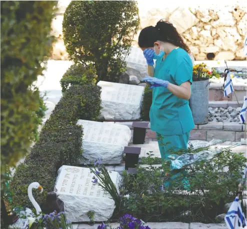  ?? Ronen Zvulun / REUTERS ?? An Israeli nurse stands next to soldiers’ graves during Remembranc­e Day ( Yom Hazikaron) on Tuesday in Jerusalem.
As the spread of COVID-19 continues, some businesses, such as barber shops and hardware stores, have reopened.