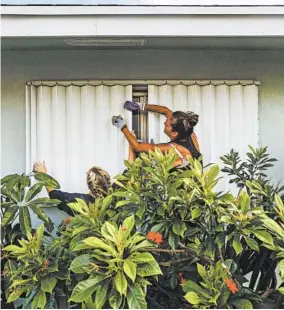  ?? SAUL MARTINEZ/THE NEW YORK TIMES ?? People place protective shutters on the windows of their home Saturday in Lake Worth, Fla., in advance of the storm.