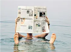  ??  ?? Floating in the Dead Sea with a copy of the Jordan Times. Other papers are available