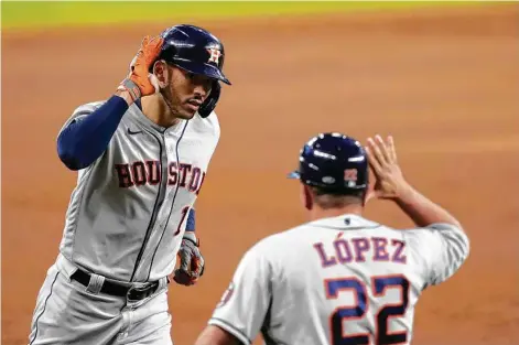  ?? Tony Gutierrez / Associated Press ?? Carlos Correa and first base coach Omar Lopez celebrate Correa’s solo home run in the third, the shortstop’s 20th homer of the season.