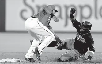  ?? Associated Press ?? Cleveland Indians’ Carlos Santana, right, is tagged out by Texas Rangers shortstop Elvis Andrus at second base while trying to steal Saturday during the third inning in Arlington, Texas.