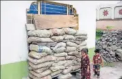  ?? AFP ?? Children walk past a window covered with bags to protect the house from bullets during crossborde­r firing from Pakistan.