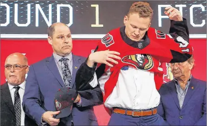  ?? AP PHOTO ?? Brady Tkachuk puts on an Ottawa Senators jersey after being selected by the team during the NHL hockey draft in Dallas on June 22.