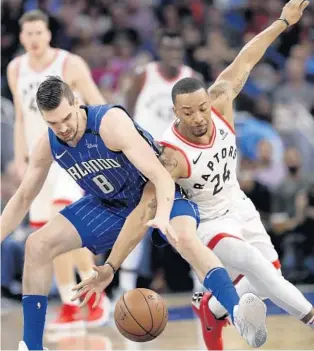  ?? JOHN RAOUX/ASSOCIATED PRESS ?? Magic swingman Mario Hezonja (8) and Raptors G Norman Powell fight for a loose ball during the first half of Tuesday’s game at Amway Center. Hezonja scored 8 points, while Powell gave the Raptors 10 points.