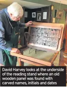  ??  ?? David Harvey looks at the underside of the reading stand where an old wooden panel was found with carved names, initials and dates