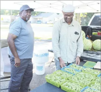  ?? Katie West • Times-Herald ?? The Forrest City Farmers Market, open each Saturday from 8 a.m. until noon on the Civic Center parking lot, has fresh produce available from local gardens. Local gardeners Grady Kidd, left, and Willie Bean look over a table of fresh products for sale. The market will open again at 8 a.m., tomorrow.