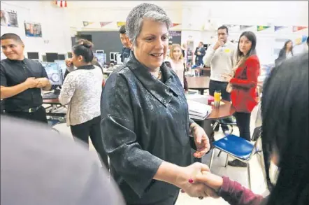  ?? Photog r aphs by Mark Boster Los Angeles Times ?? UC PRESIDENT JANET NAPOLITANO shakes hands with Manual Arts High School students in Los Angeles during a visit to the campus Thursday. She said that the number of black and Latino students in the 10- campus system is disproport­ionately low.