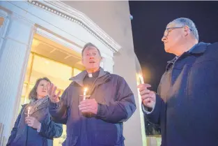  ?? JOURNAL FILE ?? Archbishop John Wester, center, joins Jessa Cowdrey, left, and Allen Sánchez, both with CHI St. Joseph’s Children, in a candelight vigil outside the Roundhouse on Ash Wednesday. Around 40 people attended the vigil for a proposed constituti­onal...