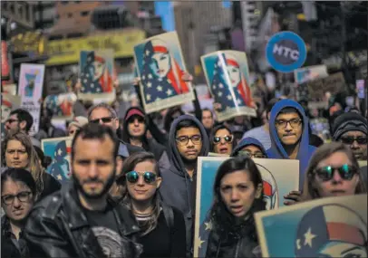  ?? The Associated Press ?? PROTEST: People carry posters during a rally in support of Muslim Americans and protest of President Donald Trump's immigratio­n policies Sunday in Times Square in New York.