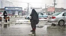  ?? ?? A woman in burqa begs along a street during a snowfall in Kabul. AFP