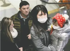  ?? DAVID RYDER / REUTERS ?? Travellers wearing masks arrive in the U. S. this week on a direct flight from China.