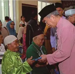  ?? [FOTO CHE RANI CHE DIN/BH] ?? Wan Junaidi menyerahka­n sumbangan kebajikan sempena Ramadan kepada 810 warga emas, OKU dan anak yatim di Masjid Darul Hana, Kuching, semalam.