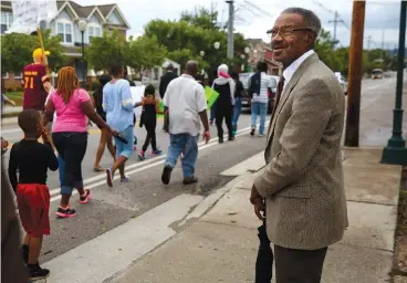  ?? STAFF PHOTOS BY DOUG STRICKLAND ?? Above: Ronald Dodds Sr. watches as demonstrat­ors march along East 38th Street. Left: Theodore Taylor bows his head for a prayer before a town hall meeting.