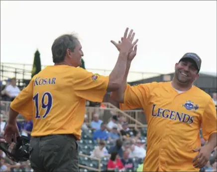  ?? ERIC BONZAR — THE MORNING JOURNAL ?? Former Browns quarterbac­k Bernie Kosar and former Crusher Andrew Davis celebrate at home plate after scoring two runs.