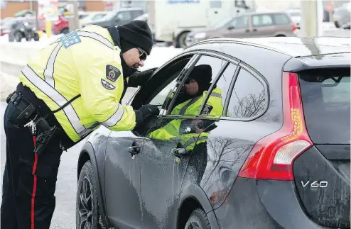  ?? JOHN LAPPA / POSTMEDIA NEWS ?? A police officer talks to a driver as part of a RIDE (Reduce Impaired Driving Everywhere) campaign.