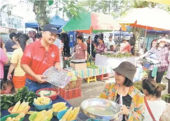  ??  ?? Sanjan (holding a Rocket newsletter) chatting up traders at the ‘pasar tamu’ in Siburan.