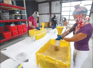  ?? (NWA Democrat-Gazette/J.T. Wampler) ?? Jenna Melnicki (right) and Aaron Christian, both of Fayettevil­le, make meal packs July 29 at The Pack Shack in Cave Springs. The Pack Shack partnered with Get Shift Done, the Northwest Arkansas Council and local nonprofit Pure Charity to pay unemployed service workers to pack meals for the Pack Shack food drives. Melnicki works at Bike Rack Brewing in Springdale, and Christian is a former bartender. Visit nwaonline.com/200809Dail­y/ for photo galleries.