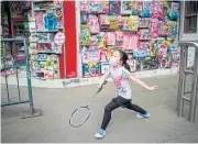  ?? AFP ?? A girl, wearing a face mask, plays badminton in Wuhan.