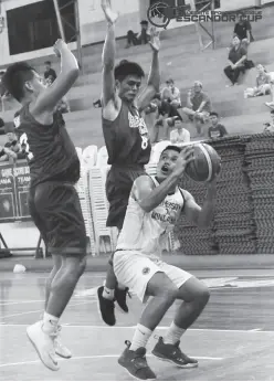  ??  ?? UM WILDCAT Jay-Mar Mejala (with ball) fakes off two DMMA defenders during their match-up at the Davao City Recreation Center. (CSL-Escandor Cup photo)