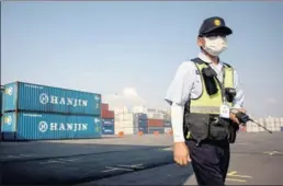  ?? ED JONES / AFP ?? A security guard walks by containers at the Hanjin Incheon Container Terminal in Seoul. China COSCO Shipping Corp said it may consider buying some container-terminal assets of the troubled Hanjin Shipping Co.