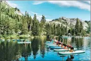  ?? AP ?? Participan­ts work out on paddle boards during a trip to North Lake Tahoe, California. Wellness tourism is booming, with travelers planning trips with a goal of improving their health and well-being.