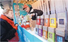  ?? RICHARD DREW/ASSOCIATED PRESS ?? Anthony Cherrie, right, describes Fatty Sundays chocolate-covered pretzels to a customer at the Union Square Holiday Market in New York City.