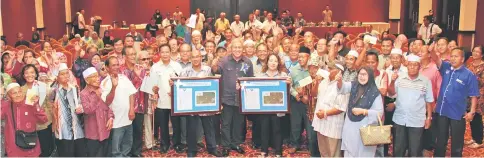  ??  ?? Awang Tengah (front sixth right) is seen during a photo call with recipients of land compensati­on, land titles and communal reserve titles.