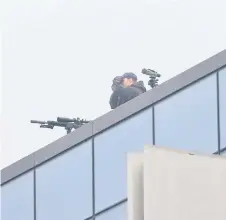  ??  ?? A police sniper monitors the surroundin­gs from the roof of the Christchur­ch High Court building.