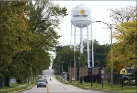  ?? ASSOCIATED PRESS FILE PHOTO ?? A lone resident of Benton Harbor, walks across Britain Street, Oct. 22, near the city’s water tower.