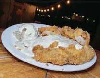  ??  ?? Chicken-fried steak comes with sides like onion rings and mashed potatoes with gravy at Spechts Texas north of San Antonio.
